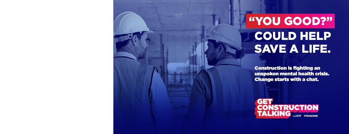Two construction workers walking ahead and talking to eachother. 